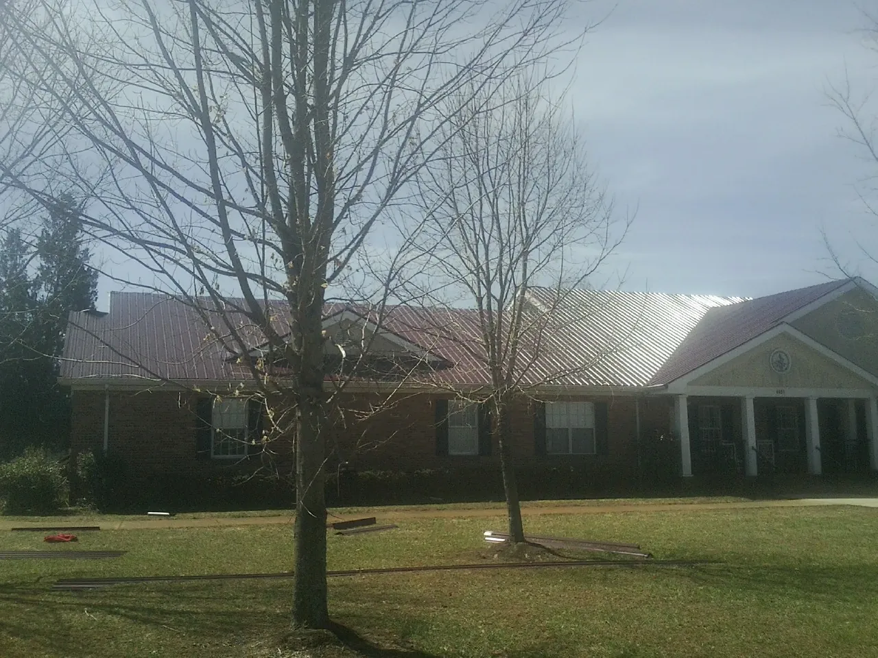 Red metal roof on a brick building seen from the front lawn in Colbert