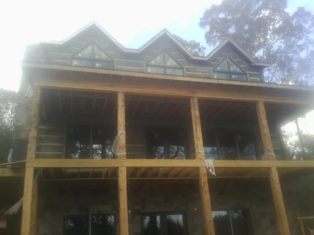 Dormers and porch framing on a large log home under construction — Roof Coating work by our crew in Colbert