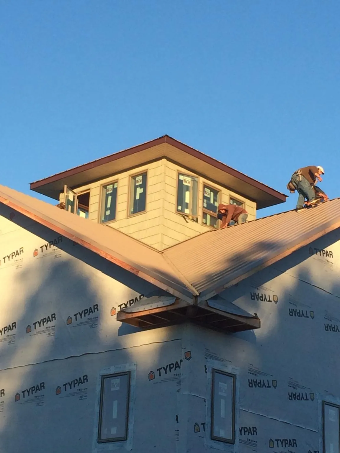 Roofers working around a rooftop cupola on a new metal roof at sunset — Roof Waterproofing in Colbert by Roofing Brothers